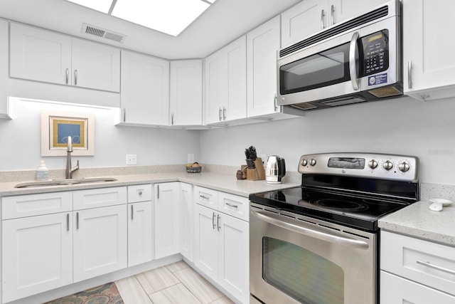 kitchen with white cabinetry, appliances with stainless steel finishes, sink, and light stone counters