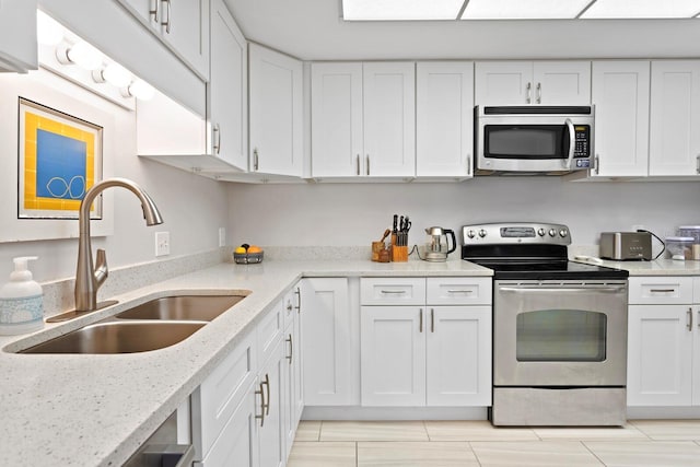 kitchen with light stone counters, sink, stainless steel appliances, and white cabinets