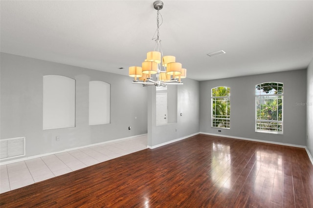 spare room with hardwood / wood-style floors and a notable chandelier