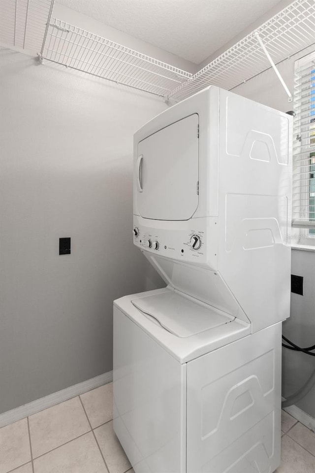 clothes washing area with stacked washer and dryer and light tile floors