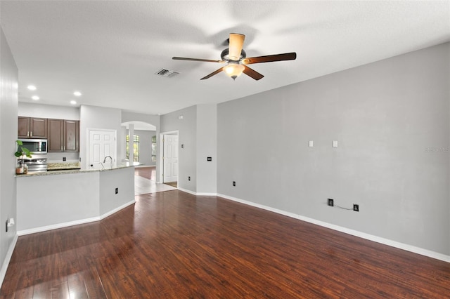 unfurnished living room with ceiling fan and dark wood-type flooring