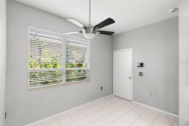 spare room with ceiling fan and light tile flooring