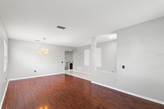 spare room with wood-type flooring and a notable chandelier