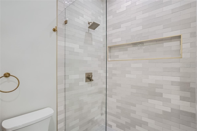 bathroom featuring a shower with door and toilet