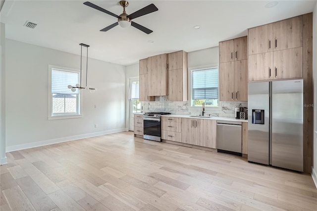 kitchen featuring light hardwood / wood-style flooring, stainless steel appliances, backsplash, hanging light fixtures, and sink