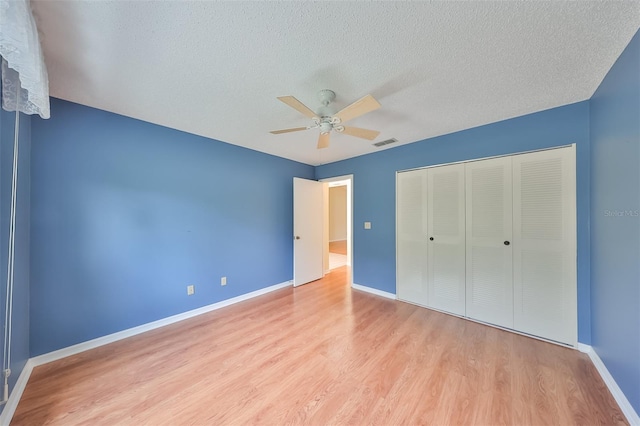 unfurnished bedroom featuring a closet, a textured ceiling, ceiling fan, and light hardwood / wood-style floors