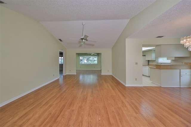 unfurnished living room featuring light hardwood / wood-style flooring, vaulted ceiling, and a textured ceiling