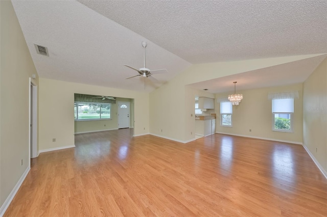 spare room with ceiling fan with notable chandelier, a textured ceiling, vaulted ceiling, and light wood-type flooring