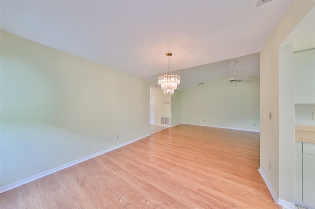 unfurnished room featuring lofted ceiling, light hardwood / wood-style flooring, and ceiling fan with notable chandelier