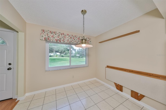 unfurnished dining area with light tile floors and a textured ceiling