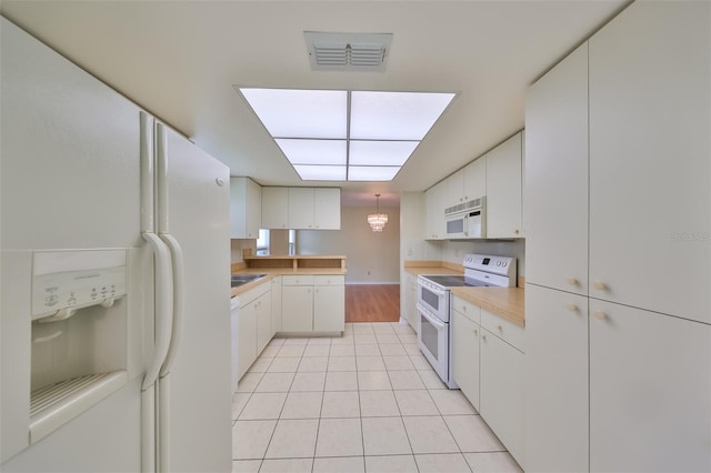 kitchen with white cabinetry, white appliances, and light tile flooring