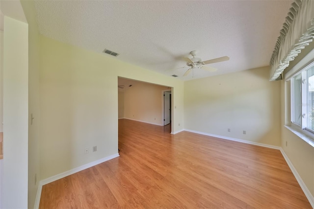 empty room with ceiling fan, a textured ceiling, and light wood-type flooring