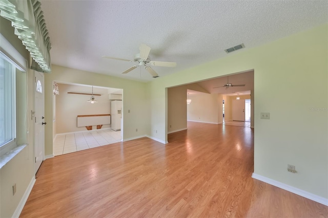 spare room featuring light hardwood / wood-style flooring, ceiling fan, and a textured ceiling