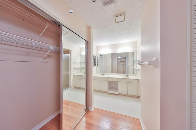 interior space with sink, a textured ceiling, light tile floors, and ensuite bathroom