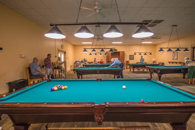 rec room featuring billiards, ceiling fan, hardwood / wood-style flooring, and a paneled ceiling