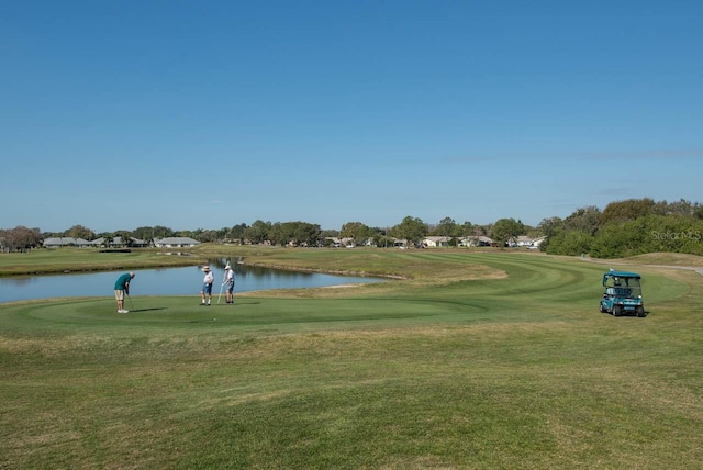 surrounding community with a water view and a lawn