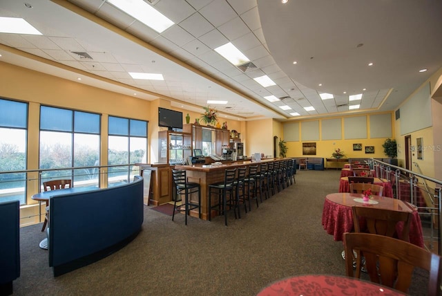 dining room featuring a drop ceiling, carpet, and a towering ceiling