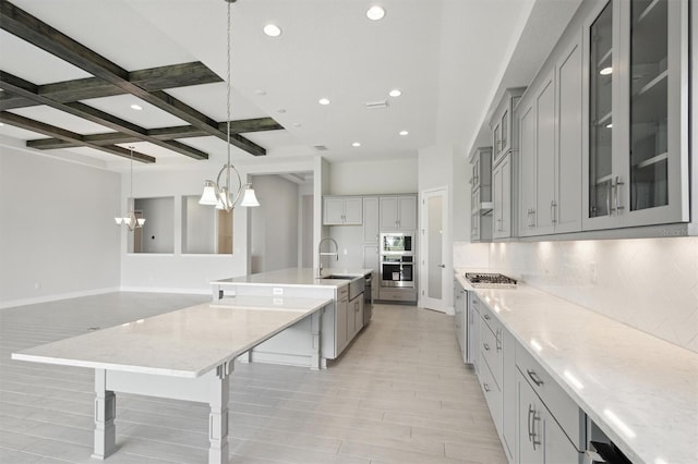 kitchen with backsplash, stainless steel appliances, a large island, and coffered ceiling