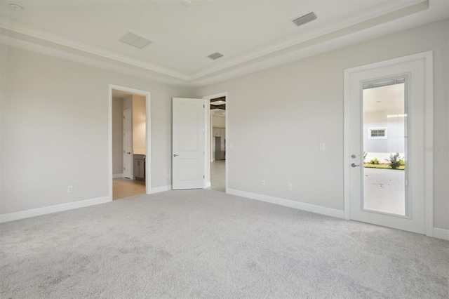 unfurnished bedroom with carpet floors, a raised ceiling, and ensuite bathroom