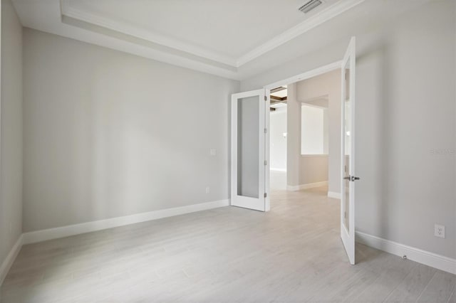 empty room with visible vents, baseboards, french doors, light wood finished floors, and a raised ceiling