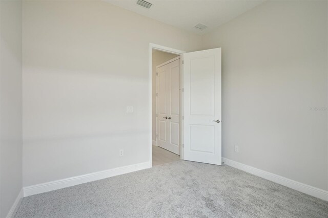 carpeted empty room featuring visible vents and baseboards