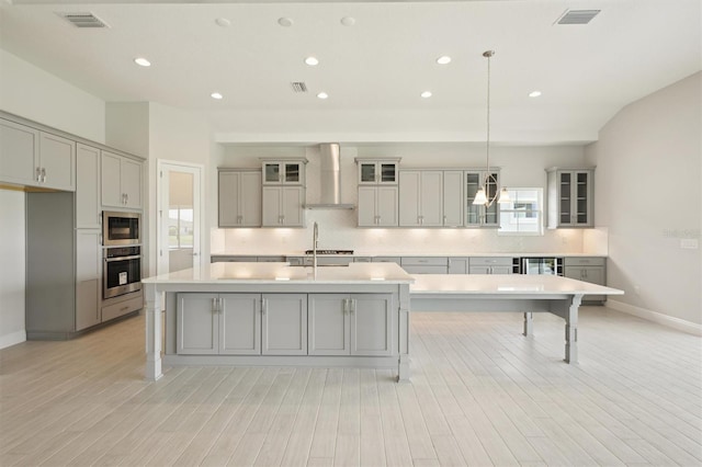 kitchen featuring stainless steel appliances, visible vents, wall chimney range hood, and gray cabinetry