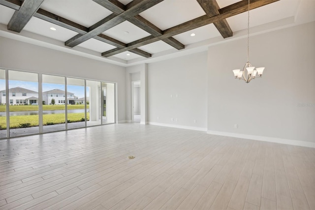 empty room with light hardwood / wood-style flooring, a chandelier, coffered ceiling, a high ceiling, and beamed ceiling