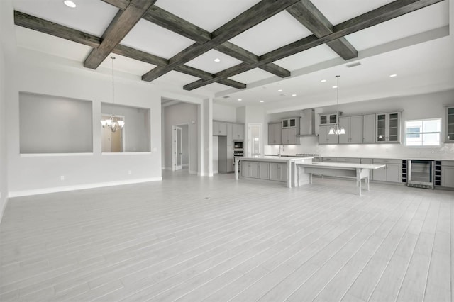 unfurnished living room featuring light hardwood / wood-style flooring, coffered ceiling, beverage cooler, a notable chandelier, and beamed ceiling