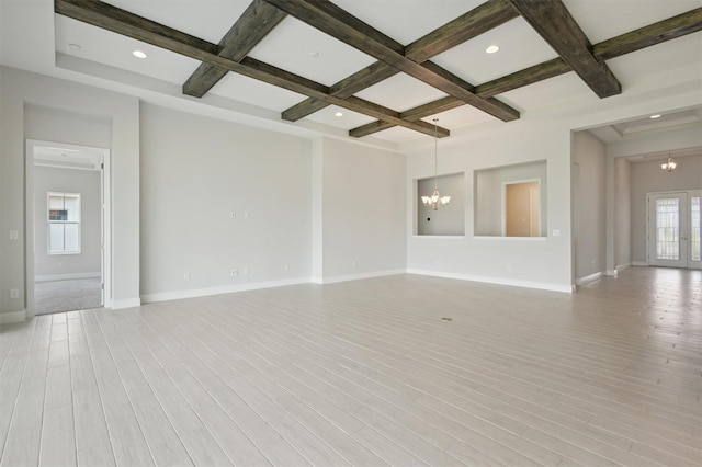 spare room featuring light hardwood / wood-style flooring, a notable chandelier, beam ceiling, and coffered ceiling