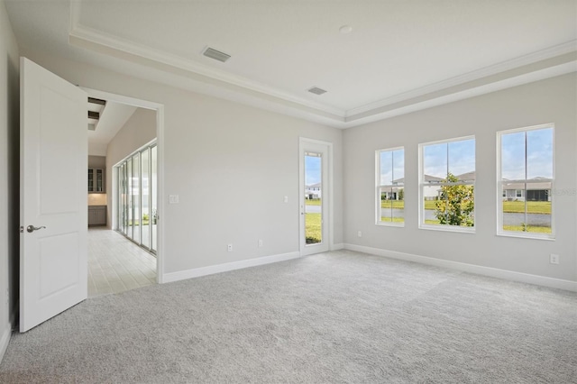 unfurnished room featuring visible vents, baseboards, light colored carpet, a tray ceiling, and crown molding