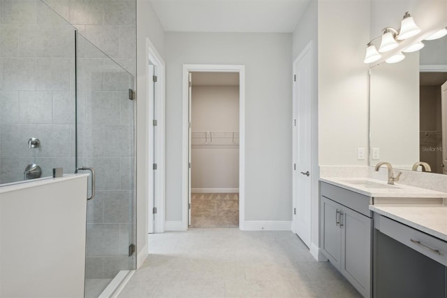 full bath with vanity, baseboards, a spacious closet, tile patterned floors, and a stall shower