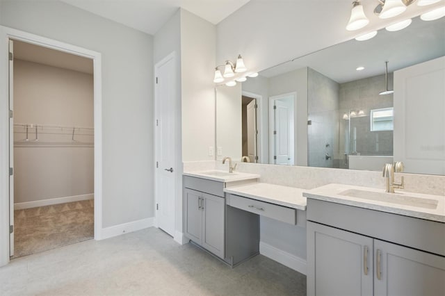 full bath with double vanity, a shower stall, a walk in closet, and a sink