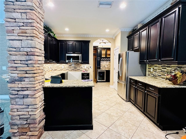 kitchen with tasteful backsplash, stainless steel appliances, light tile floors, and ornamental molding