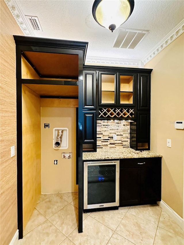 kitchen featuring light tile flooring, light stone countertops, crown molding, beverage cooler, and tasteful backsplash