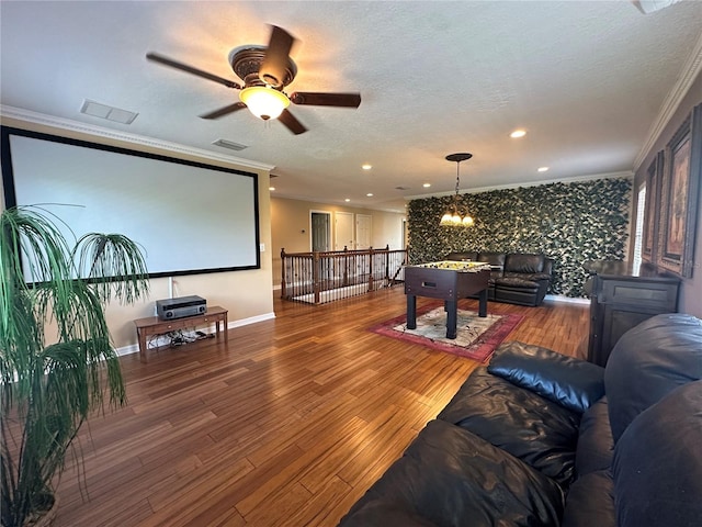 cinema featuring wood-type flooring, a textured ceiling, ceiling fan with notable chandelier, and crown molding