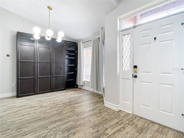 entrance foyer with a notable chandelier, a healthy amount of sunlight, and light wood-type flooring