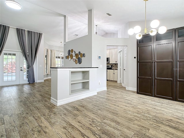 kitchen with tasteful backsplash, hanging light fixtures, a notable chandelier, and light wood-type flooring