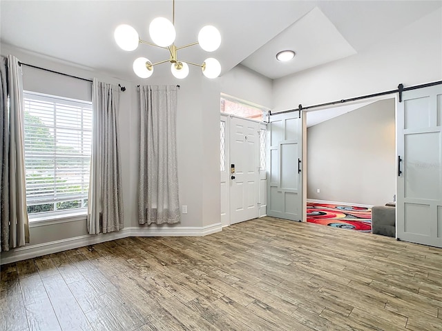 foyer featuring hardwood / wood-style floors, a barn door, and an inviting chandelier