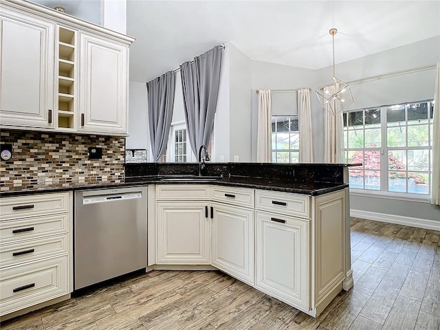 kitchen featuring dishwasher, sink, light hardwood / wood-style flooring, a chandelier, and dark stone counters