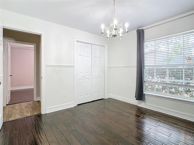 unfurnished bedroom featuring a notable chandelier, dark hardwood / wood-style flooring, and a closet