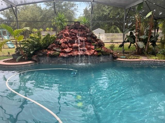 view of pool featuring pool water feature and glass enclosure