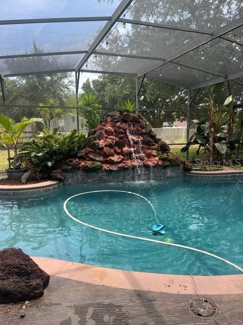 view of pool with a lanai and pool water feature