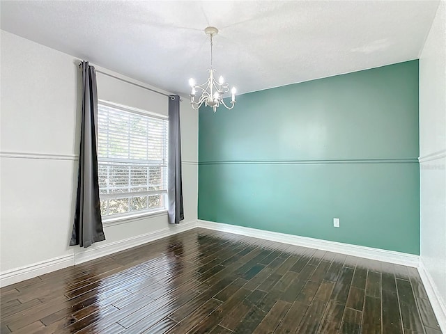 unfurnished room with a textured ceiling, an inviting chandelier, and dark wood-type flooring