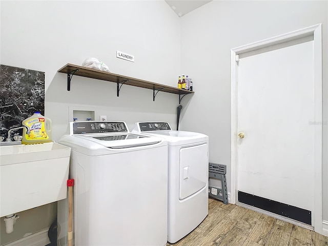 laundry room featuring separate washer and dryer, light hardwood / wood-style flooring, and sink