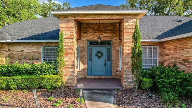 property entrance featuring brick siding and roof with shingles