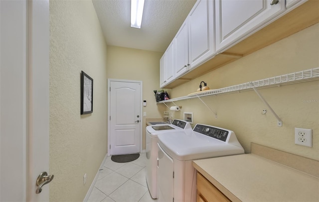 clothes washing area featuring cabinets, independent washer and dryer, light tile floors, washer hookup, and a textured ceiling