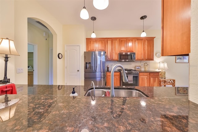 kitchen featuring decorative light fixtures, appliances with stainless steel finishes, sink, and dark stone counters