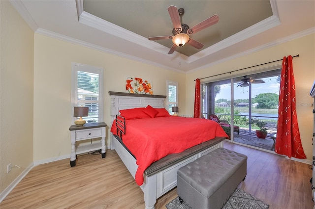 bedroom featuring hardwood / wood-style floors, ceiling fan, a tray ceiling, and access to exterior