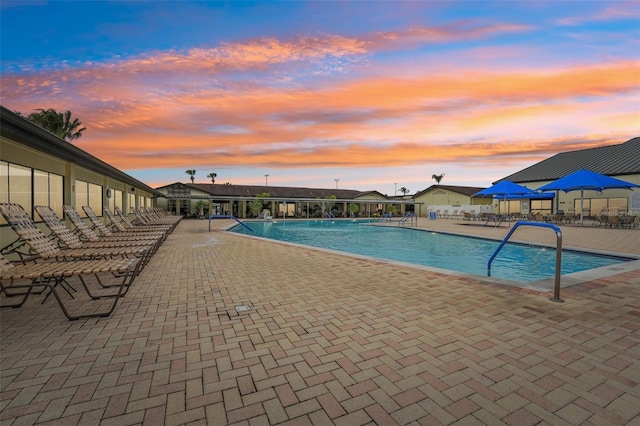 pool at dusk featuring a patio