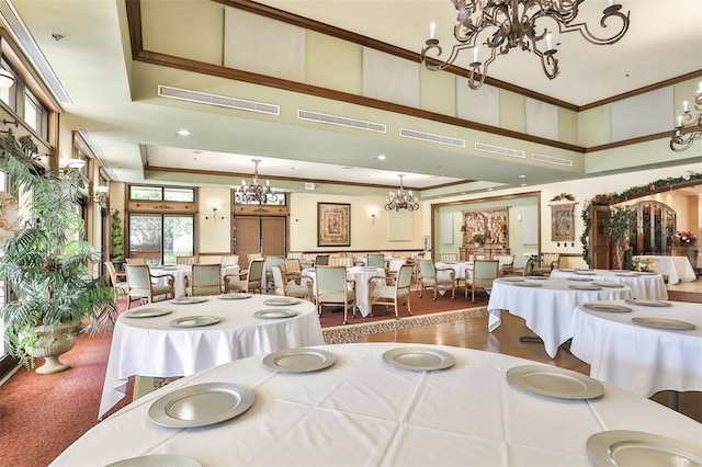 dining space with a chandelier, hardwood / wood-style floors, crown molding, and a raised ceiling